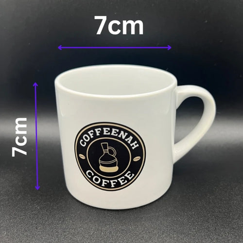 White ceramic coffee mug with a black circular 'COFFEEAH COFFEE' logo on the front, shown against a dark background with purple dimension lines indicating a height and width of 7cm.