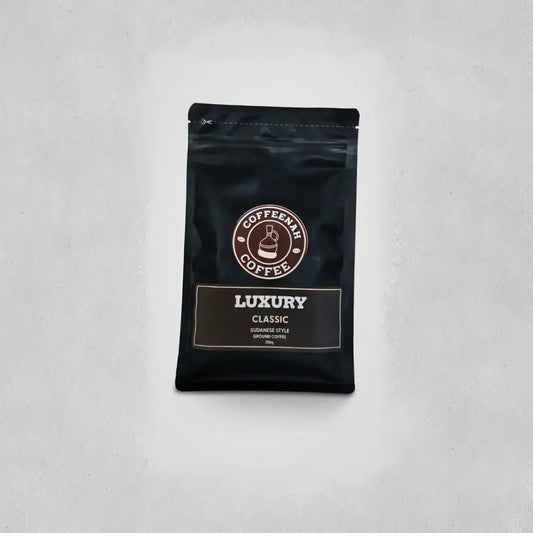 A black stand-up pouch of Coffeenum Coffee Luxury Classic coffee beans, centered on a light gray textured background.